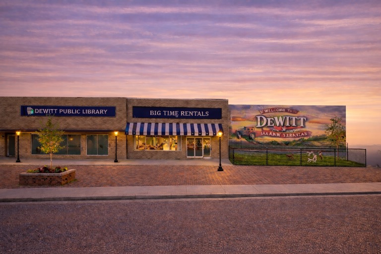 DeWitt Public Library, Big Time Rentals, and Welcome to DeWitt mural at sunset showcasing community infrastructure and downtown business vitality