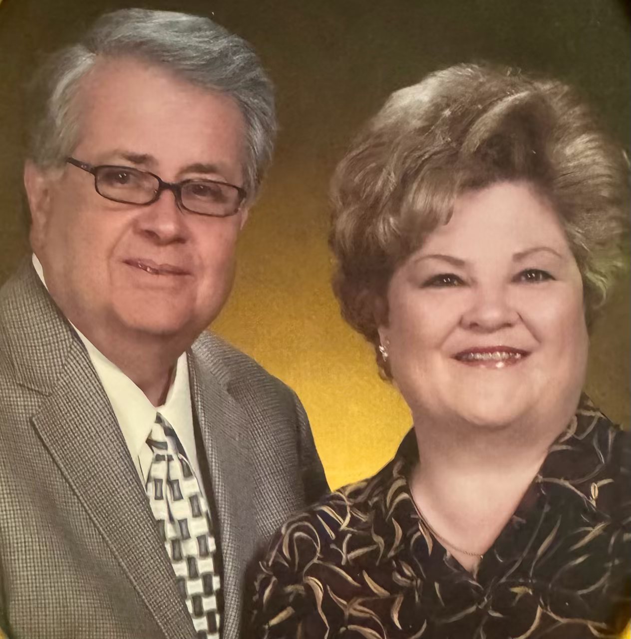 Formal family portrait featuring couple in professional attire against warm golden background showcasing family heritage and community connection